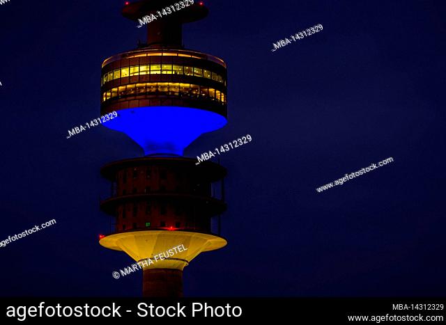 View from Olympiaberg with Olympic Tower, illuminated in Ukrainian national colors blue and yellow on the occasion of war in Ukraine, BMW Welt and Allianz Arena