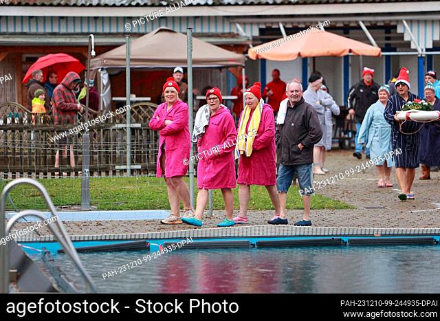 10 December 2023, Saxony-Anhalt, Osterwieck: Participants in the Advent swim enter the water in their bathrobes at 6 degrees Celsius in the Osterwieck outdoor...
