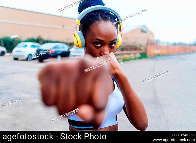 Italy, Milan, Woman with headphones punching the air in city
