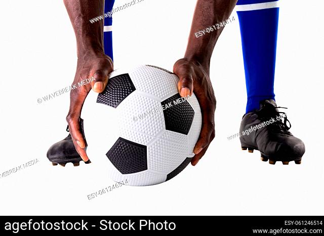 Low section of african american young male athlete holding soccer ball over white background