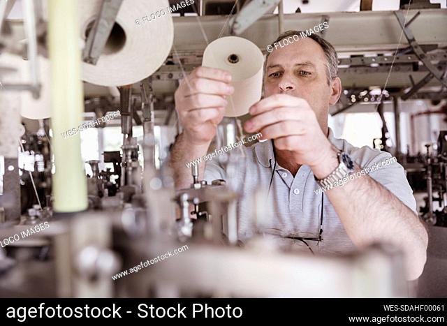 Man working with cotton reel in a textile factory