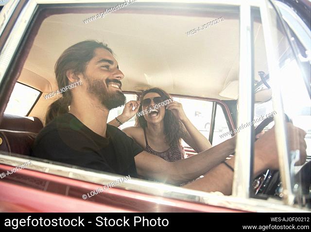 Young man driving car with young female friend on sunny day