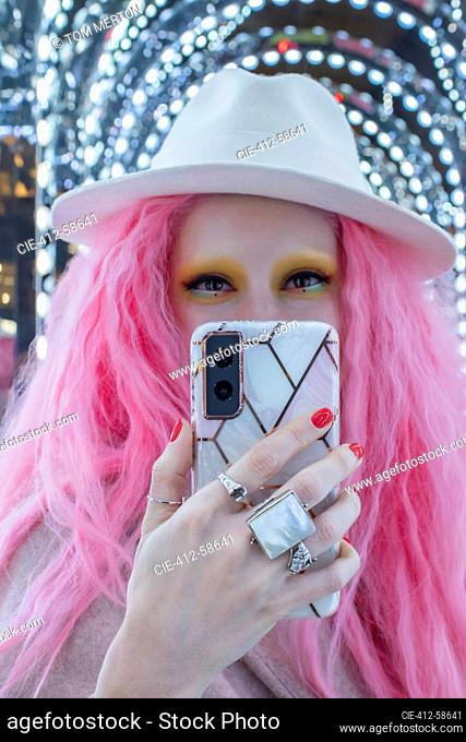 Retrato de mujer con estilo fresco con cabello rosado y fedora tomando selfie