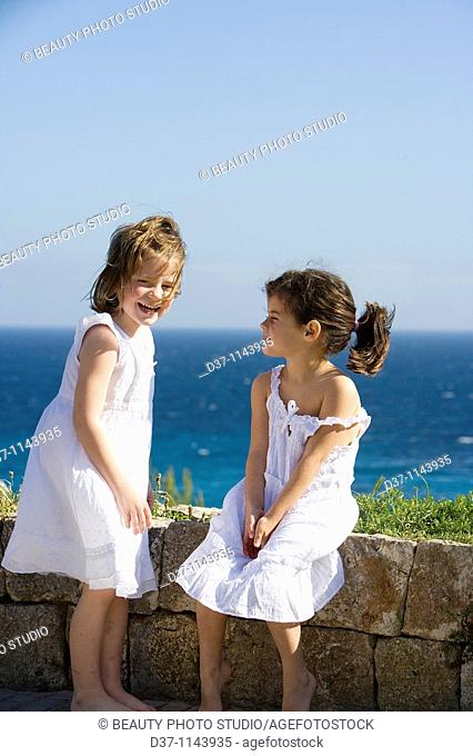 Two caucasian girls in front of a blue sea