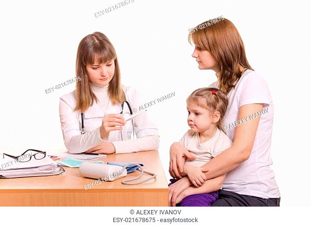 A pediatrician looks at the thermometer, sitting next to a woman with a child on her lap