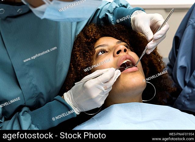 Female dentist checking patient's teeth at clinic