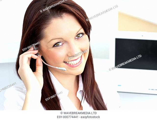 Charming young businesswoman wearing headphones smiling at the camera in her office