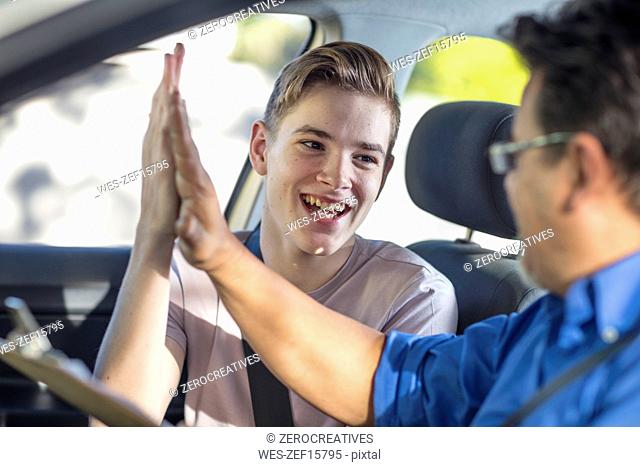 Happy learner driver and instructor giving a high five in car