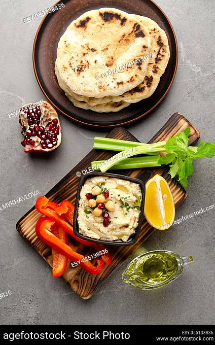 Flat lay view at vegetable Hummus dip dish topped with chickpeas and olive oil served with pita bread, celery and peppers
