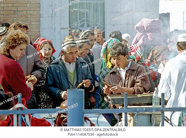 At a barbeque, Uzbeks take a small snack at the market in Khiva - grilled chicken, analogue and undated image from October 1992