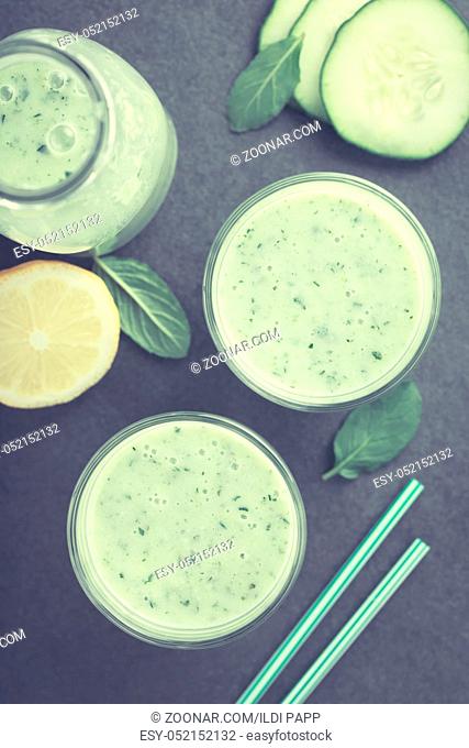 Refreshing green cucumber, yogurt, mint and lemon smoothie in glasses, photographed overhead on slate (Selective Focus, Focus on the drinks) (Digitally Altered:...