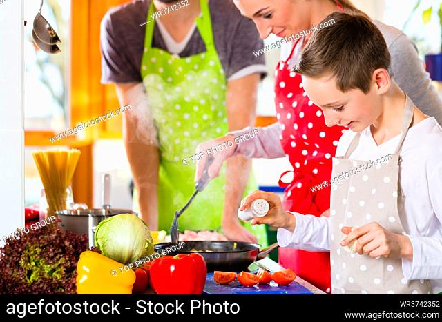 Family with Parents and children preparing healthy meal in domestic kitchen, having fun