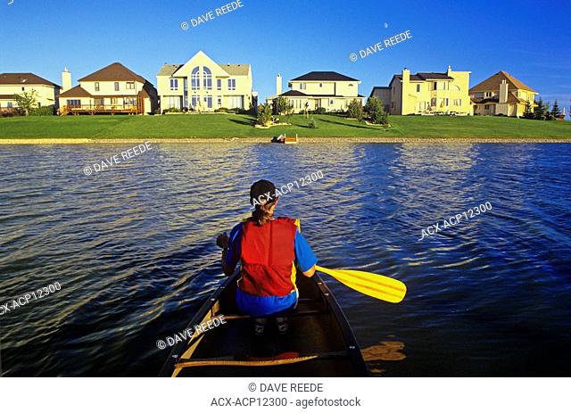 Woman canoeing on man-made lake in housing development, Winnipeg, Manitoba, Canada