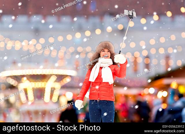 happy woman taking selfie over christmas market