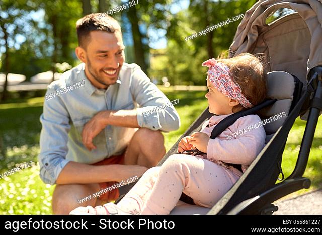 happy father with child in stroller at summer park