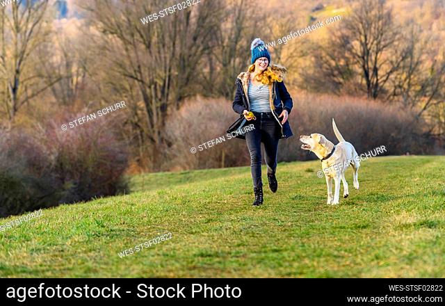 Young woman with dog running in nature