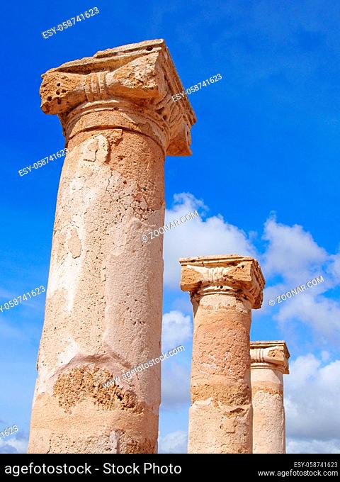 old roman columns in sunlight against a blue summer sky with clouds in kato park paphos cyprus