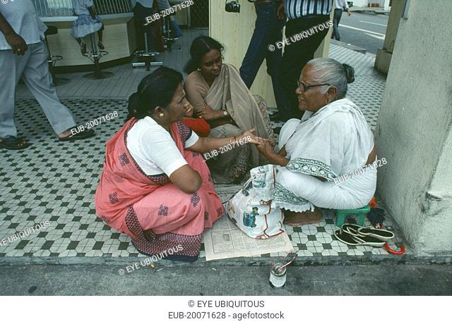 Sidewalk palm reader with women customers on Seragoon Street