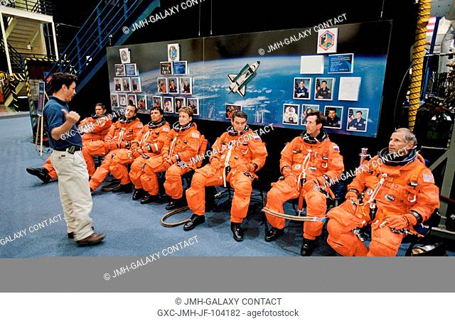 Attired in training versions of the full-pressure launch and entry suit, the STS-111 and Expedition Five crews are briefed by crew trainer Ken Trujillo in the...