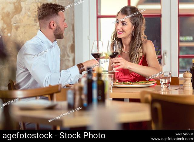 Young smiling couple enjoying red wine on their date