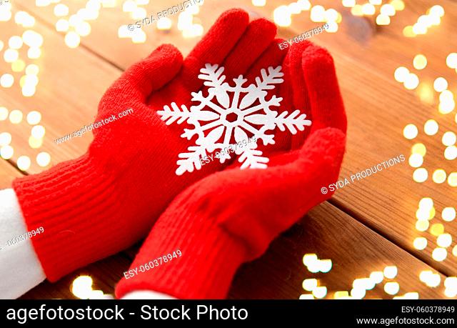 hands in red woollen gloves holding big snowflake