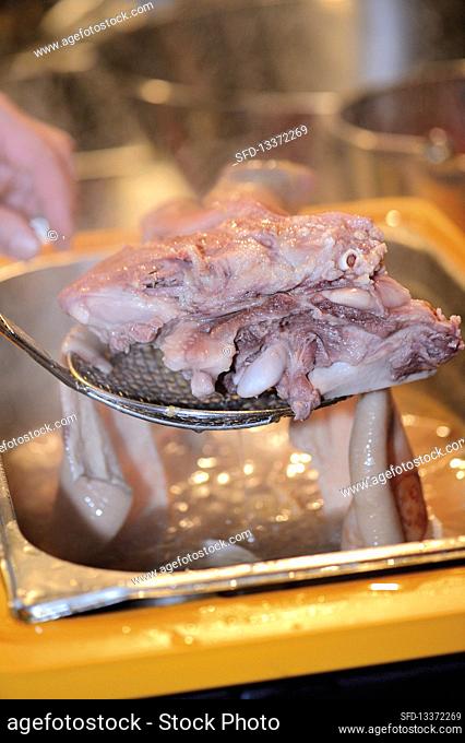 Sausages being made: cooked meat being removed from broth