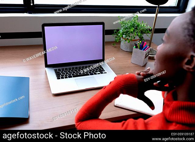 African american businesswoman sitting at desk having video call using laptop with copy space