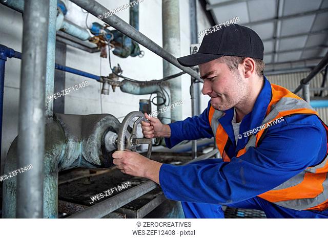 Worker turning valve in factory