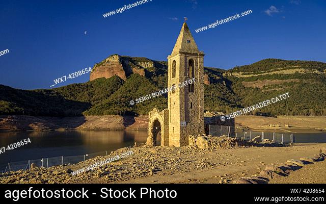 Bell tower of Sant RomÃ  de Sau at sunrise with the Sau reservoir almost empty during the 2022-23 drought (Osona, Barcelona, Catalonia, Spain)