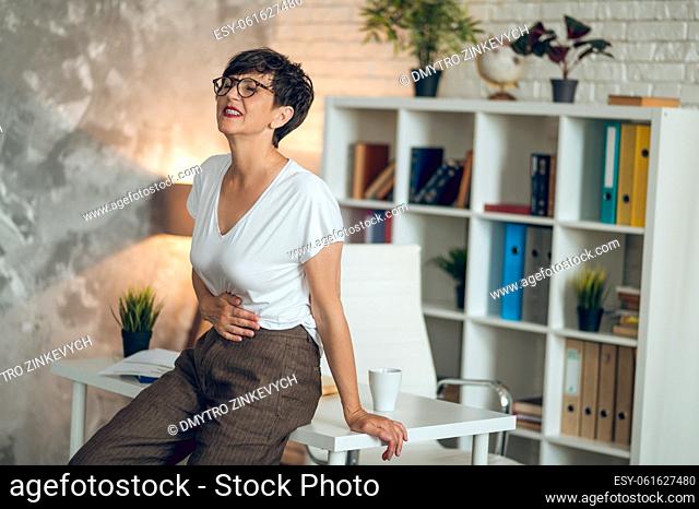 Menopause. Mature short-haired woman suffering from pains in stomach