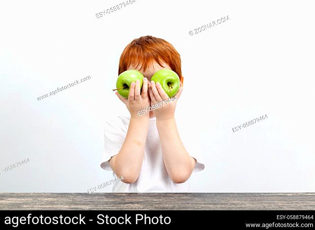red-haired boy with two green apples, closed his eyes with fruit during the game