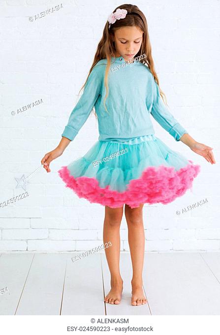 Studio portrait of cute little princess girl wearing holiday candy tutu skirt holding magic wand