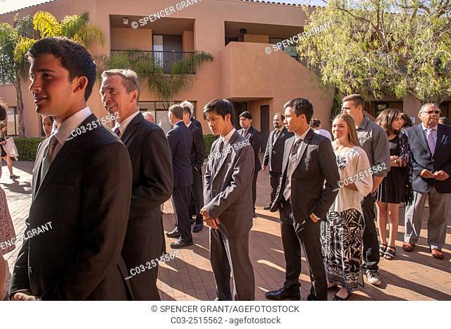 Proud multiracial teenagers of both sexes and their adult sponsors line up in afternoon sun for confirmation ceremonies at a Laguna Niguel, CA, Catholic church
