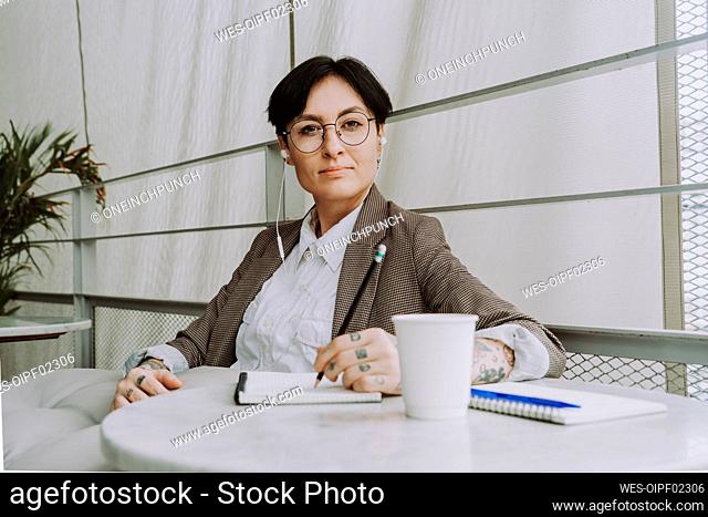 Businesswoman with short hair listening through in-ear headphones at cafe