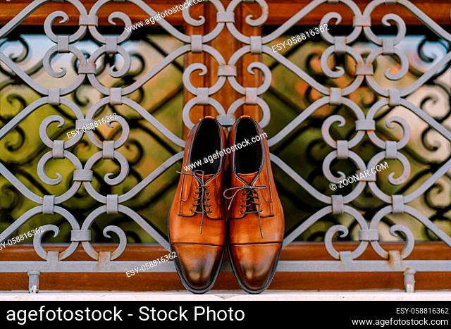 Stylish brown men's shoes made of genuine leather by the window with a metal lattice. High quality photo