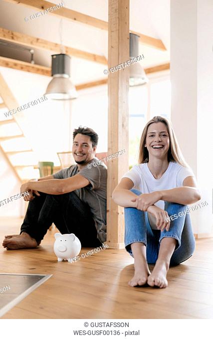 Couple sitting in new home with a piggy bank