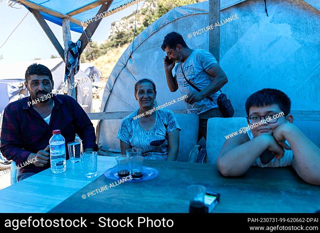 PRODUCTION - 19 July 2023, Turkey, Antakya: Ayfer Orukcu (2nd from left) lives with her son (r) and her brothers Aziz (l) and Adnan (2nd from right) in a tent...