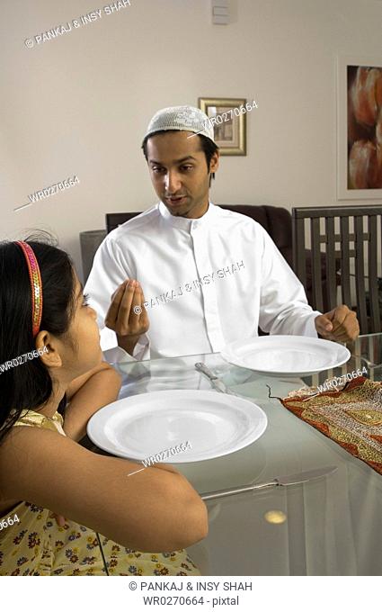 Father and daughter waiting with empty plates at the dining table