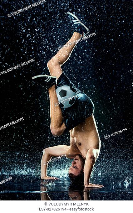 Water drops around football player on black background