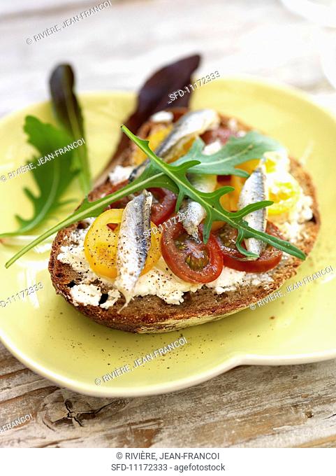 Bread topped with cream cheese, tomatoes and anchovies