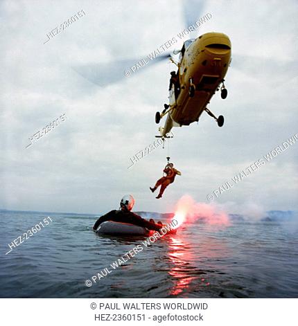 Westland Whirlwind helicopter making a rescue, 1973. A Westland Whirlwind HAS 10 beloning to RAF Search & Rescue lowers a member of the rescue team to recover a...