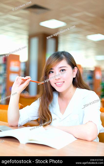 young beautiful asian girl university student with laptop in library
