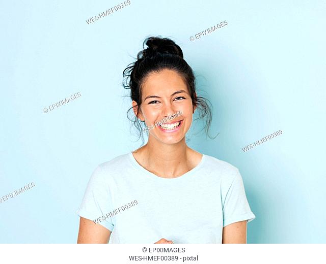 Portrait of young woman with black hair, light blue background