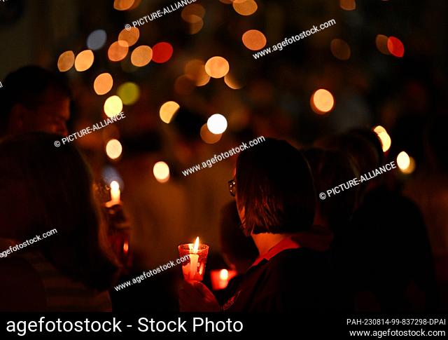 14 August 2023, Bavaria, Altötting: Numerous faithful with candles make their way to the Chapel of Grace in a traditional candlelight procession on the evening...