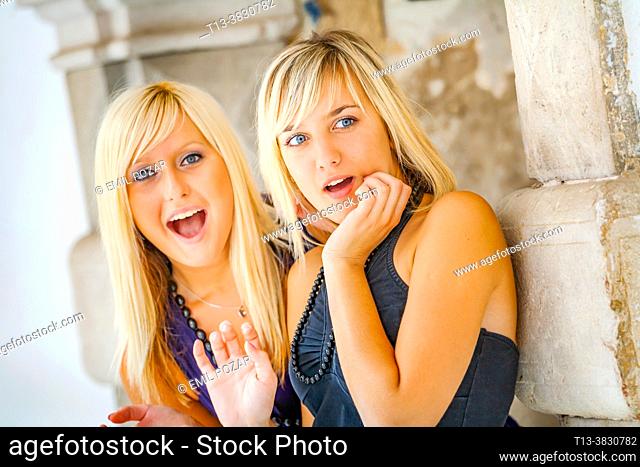 Two blondes teenage girls are intensively watching in utmost excitement
