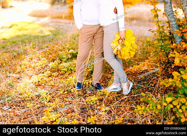 Man embracing woman in the autumn forest. Woman holding a wreath of yellow leaves in her hands. High quality photo