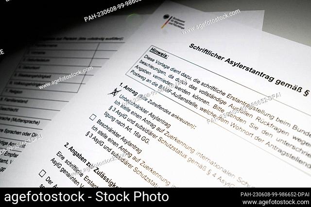08 June 2023, Lower Saxony, Hanover: ILLUSTRATION - A written asylum application from the Federal Office for Migration and Refugees (BAMF) lies on a table...
