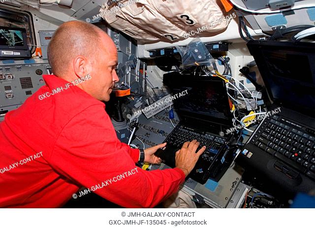 Astronaut Rick Sturckow, STS-117 commander, uses a computer on the flight deck of Space Shuttle Atlantis during flight day six activities while docked with the...
