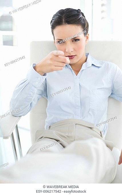 Frowning stylish brunette businesswoman pointing to the camera with her finger