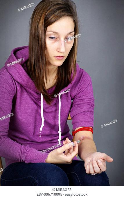 Young woman junkie, getting high injecting drugs, like heroin, with seringe in her arm great for substance abuse and narcotics related social issues